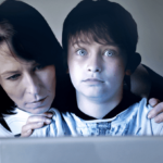 child on computer with mother watching